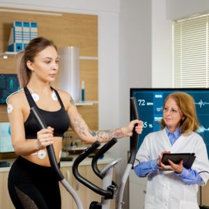 Female athlete who runs tests on the stepper and has electrodes on her and the doctor follows her